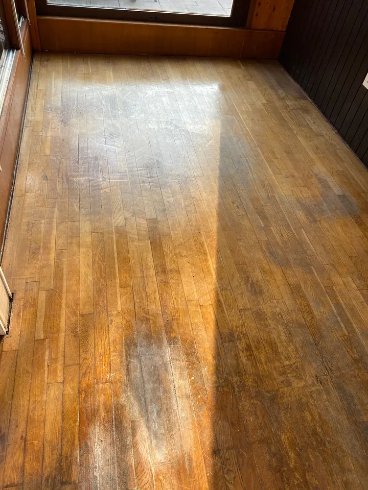 Strokenvloer in de tuinkamer met oranjebruine lak die vlekkerig en grijs is afgesleten, voor het schuren